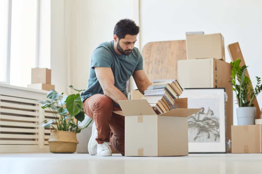A young man packing books into cardboard as her prepare for the move