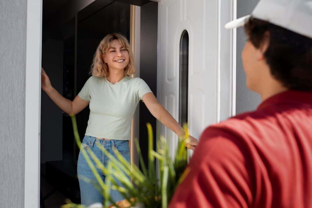 A woman greeting her new neighbour by the door