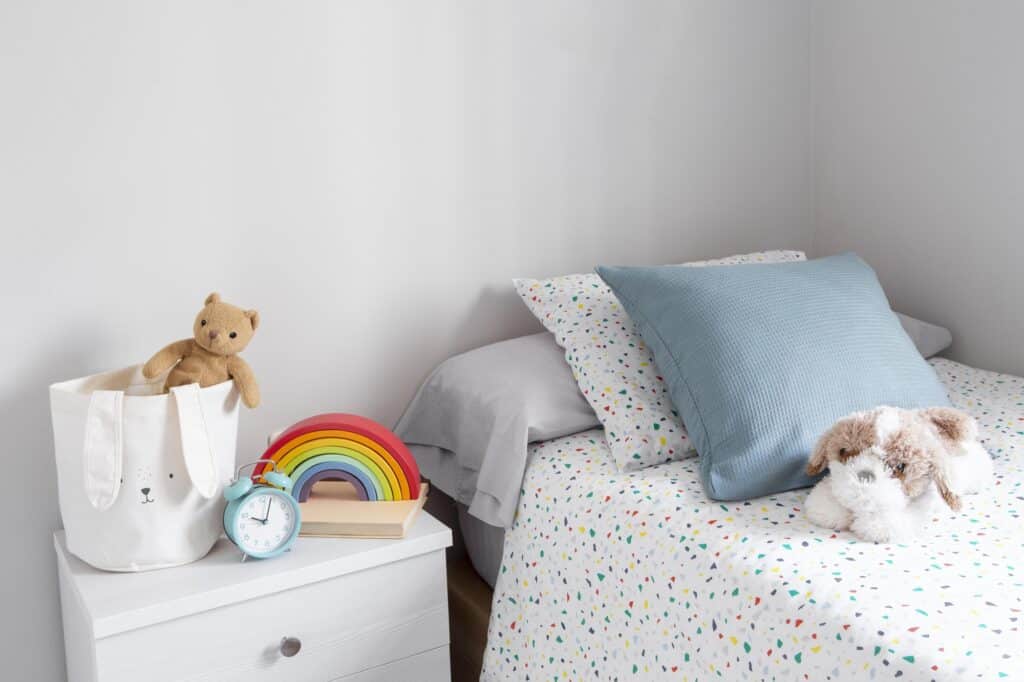 Cropped image of a kid's bedroom with bed, drawer, toys, and clock